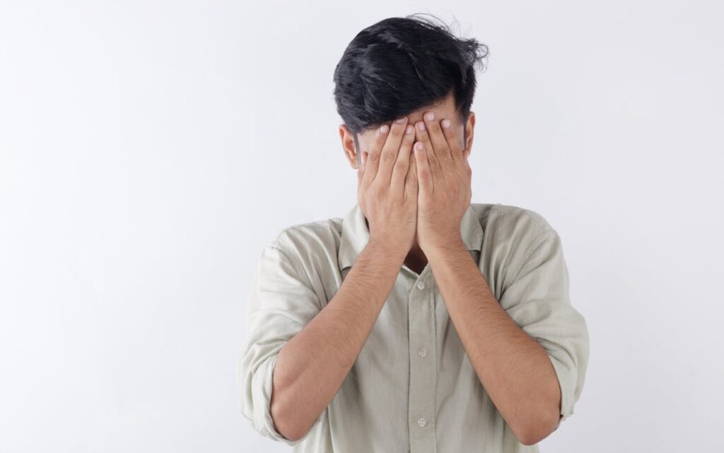hombre tapándose la cara porque está estresado y con ansiedad